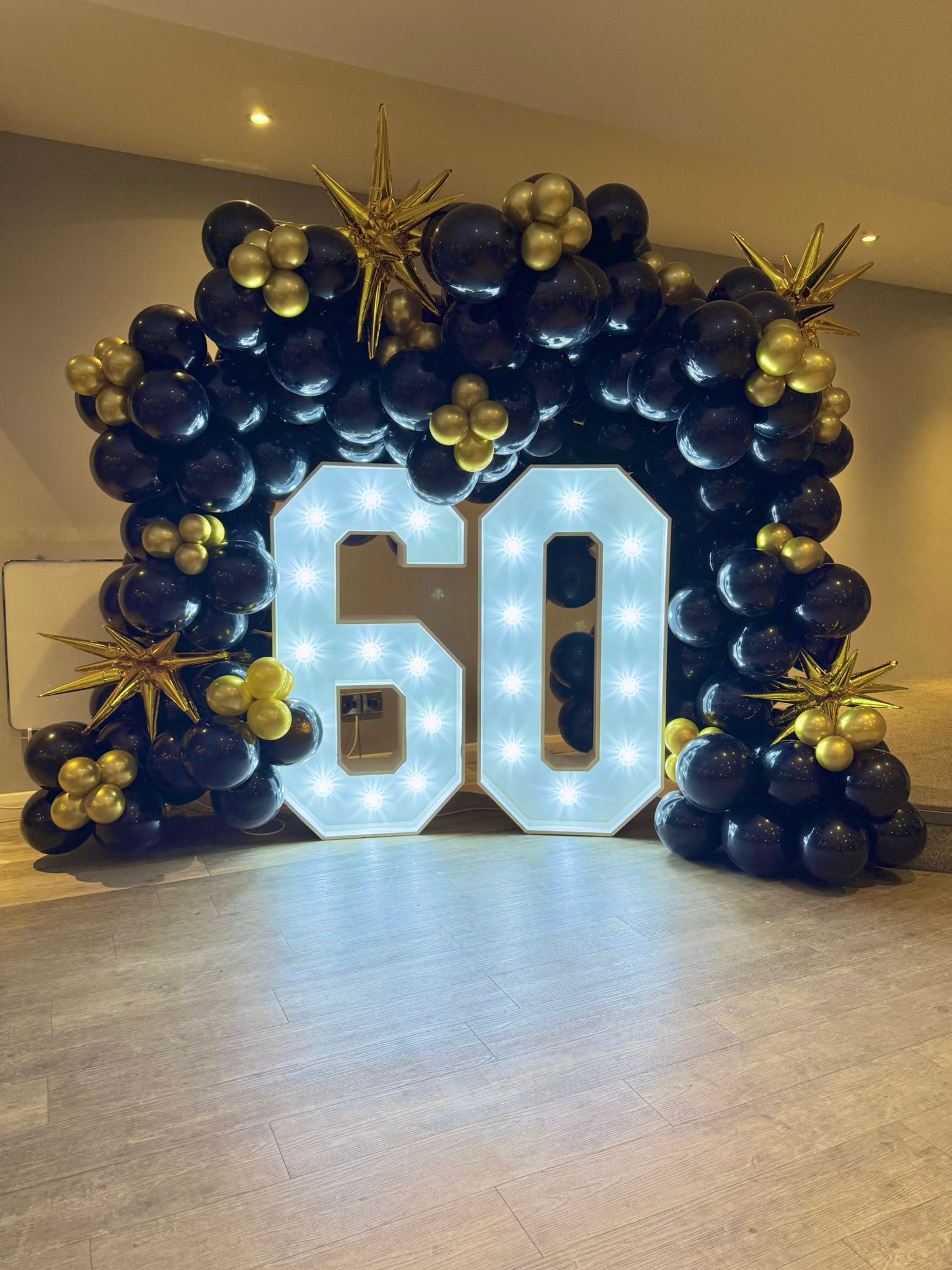 Number 60 display with black and gold balloons