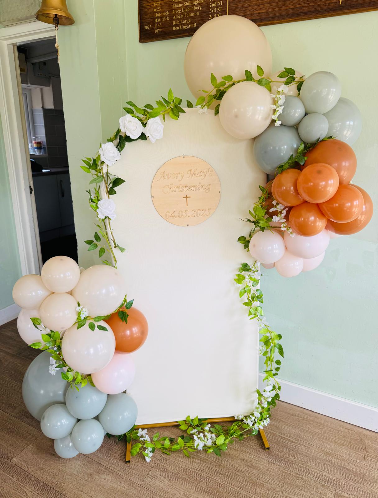 Christening balloon arch with greenery and floral accents